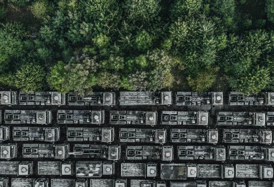 Drone shot showing rows of abandoned trucks at the edge of a forest, England, United Kingdom - stock photo